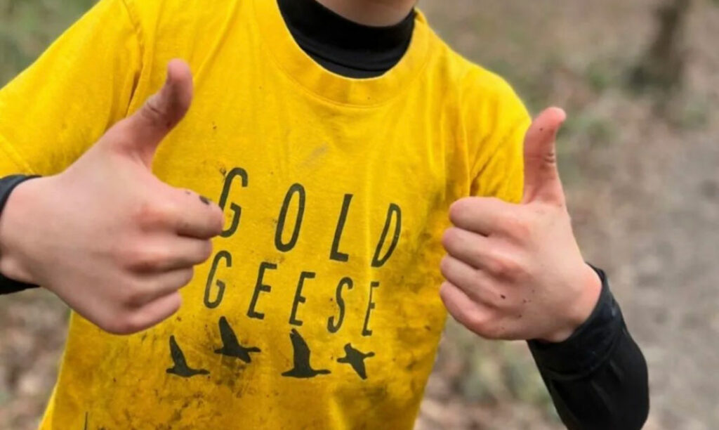 Thumbs up in a Gold Geese T-shirt