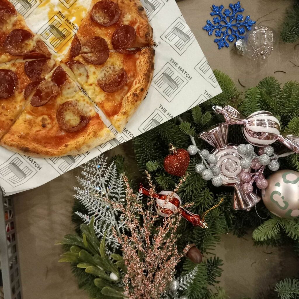 A Christmas wreath with quirky baubles in the shape of sweets, and a pizza